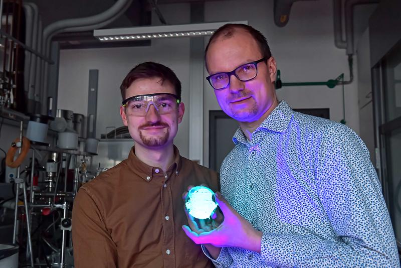 Flavio Portwich (l.) und Jun.-Prof. Dr. Robert Kretschmer mit einem fluoreszierenden Polymervlies. 