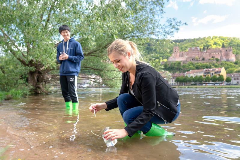 Das Bild zeigt Studierende der SRH Hochschule Heidelberg beim Entnehmen von Wasserproben aus dem Neckar.