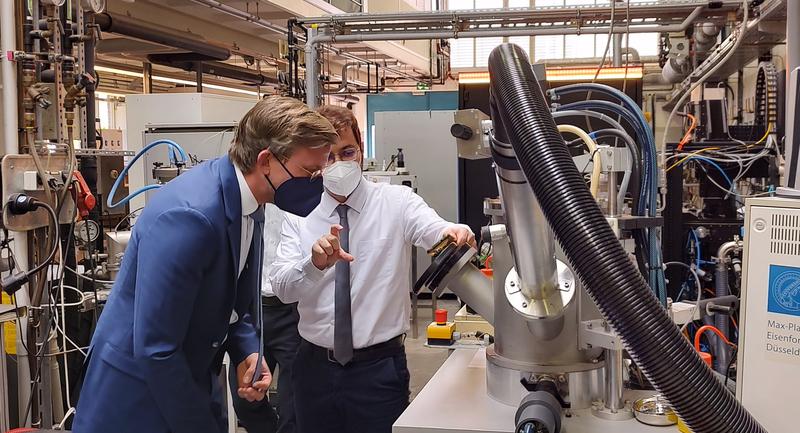 Dr. Isnaldi Souza (rechts), Gruppenleiter am Max-Planck-Institut für Eisenforschung, erklärt Staatssekretär Dr. Dirk Günnewig wie Eisenerze mit Wasserstoffplasma umweltfreundlich zu Eisen reduziert werden können.