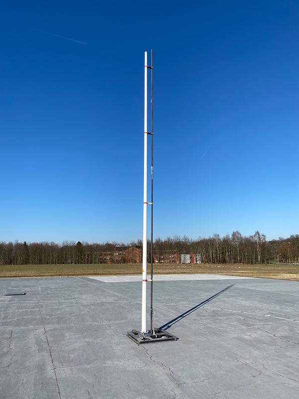 Auf dem Antennenfreifeld der PTB: Der schwarze Stab ist eine originalgroße Kopie eines der zwei Ausleger der Radarantenne für die Raumsonde JUICE (der weiße Fahnenmast dient lediglich als Support) 