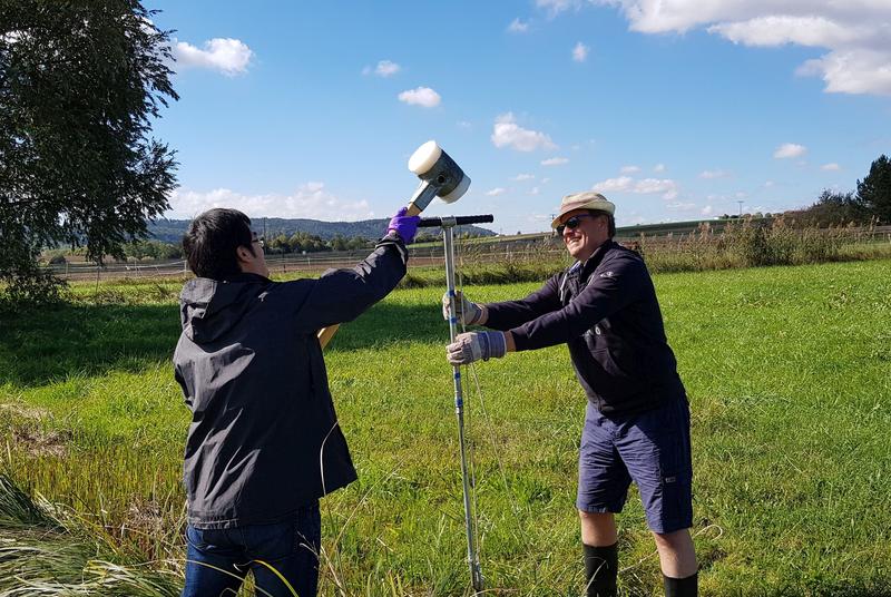 Taking a sediment core in the streambed (from left: Zhe Wang, Tillmann Lueders) .