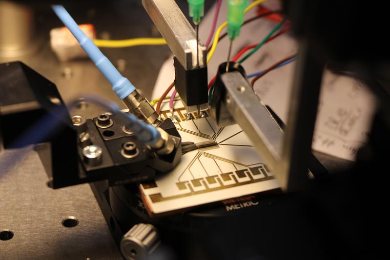 Chip mit Hochfrequenzplatine. Per Koaxialkabel (blau) werden hochfrequente elektrische Signale auf den Chip gegeben.