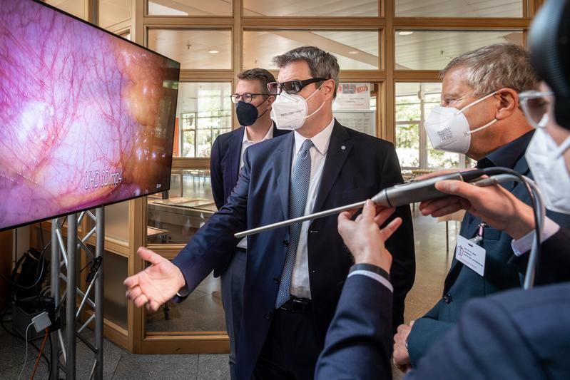 v.l.: Wissenschaftsminister Markus Blume und Ministerpräsident Markus Söder betrachten zusammen mit Herzchirurg Prof. Rüdiger Lange am Deutschen Herzzentrum München eine 3-D-Darstellung von Blutgefäßen. 