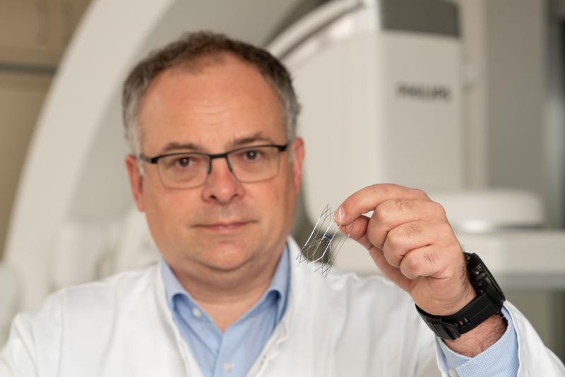 Prof. Dr. med. Ralf-Thorsten Hoffmann, Direktor von Institut und Poliklinik für Diagnostische und Interventionelle Radiologie des Dresdner Uniklinikums, hält einen der innovativen Gefäßfilter in der Hand.  