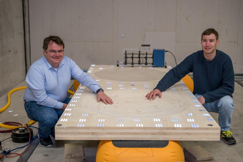 Stefan Schoenwald und Sven Vallely testen, ob die Schwingungen der Holzplatte den Berechnungen entspricht. Die in die Platte hineingefrästen Kuhlen werden mit Sand gefüllt, der die Schwingungen in Wärme verwandelt.