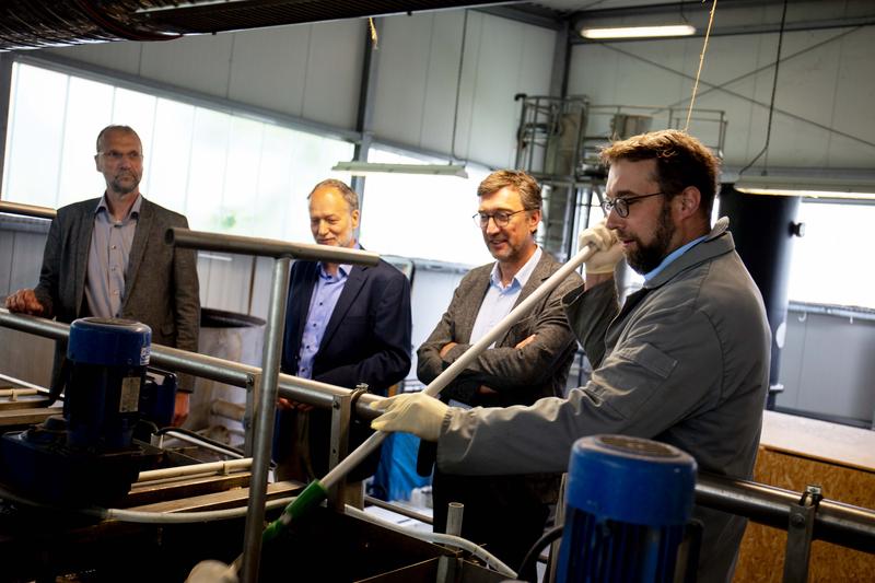 Dr. Johannes Oelerich (MELUND), Prof. Matthias Grottker und Vizepräsident Frank Schwartze der TH Lübeck schauen Dr. Kai Wellbrock bei einer Probenentnahme zu. 