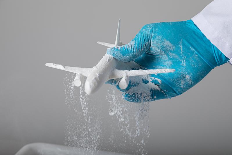 Ein Modellflugzeug, das mit dem selektiven Lasersintern gefertigt wurde, wird aus dem Pulverbett gehoben (Symbolbild).