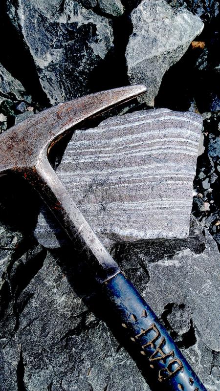 Eine gebänderte Eisenformation (banded iron-formation, BIF) mit Bändern aus Eisenoxid (dunkel) und Quarz (hell), die vor 2700 Millionen Jahren am Meeresboden abgelagert wurden. 