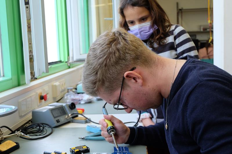 Die WissenSchaffer unterstützen Teilnehmerinnen des Girls’Day beim Löten einer Platine