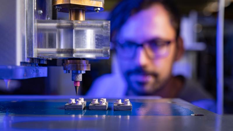 Johannes Rudolph, Wissenschaftlicher Mitarbeiter der Professur Elektrische Energiewandlungssysteme und Antriebe der TU Chemnitz, beobachtet den 3D-Druck von Gehäusen für leistungselektronische Bauelemente.