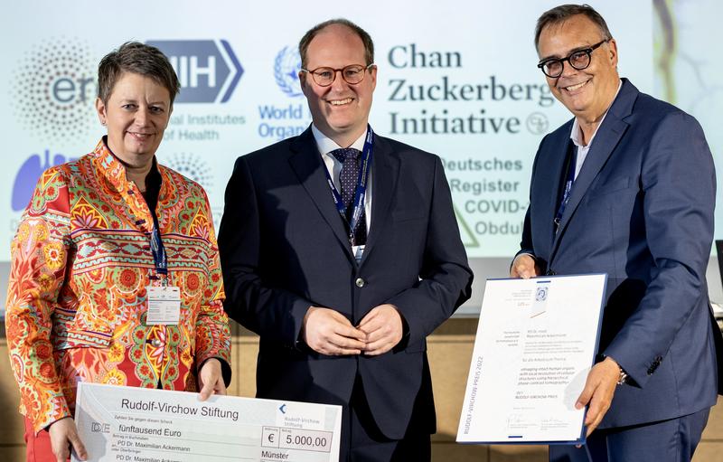Prof. Dr. Eva Wardelmann (links) und Prof. Gustavo Barreton (rechts), überreichen dem Preisträger, PD Dr. Maximilian Ackermann (Mitte), den Rudolf-Virchow-Preis 2022