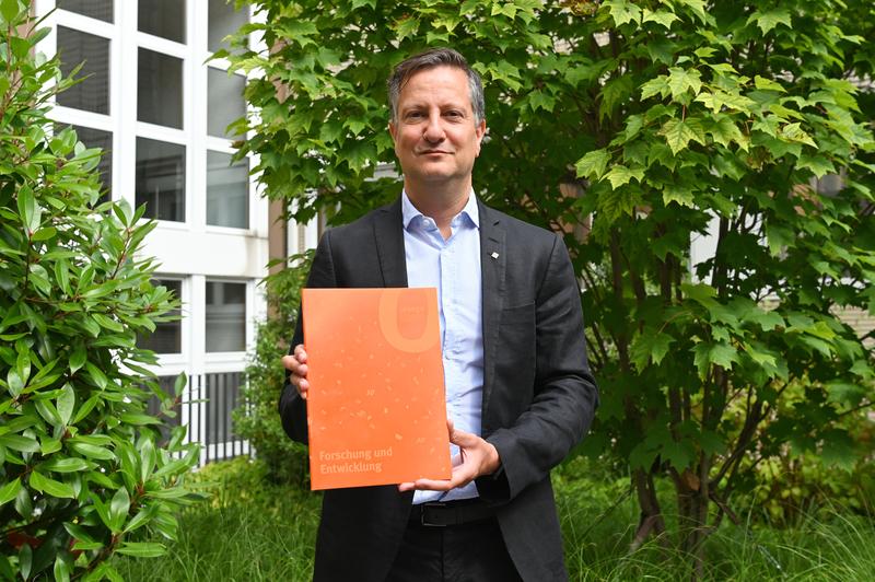 Prof. Dr. Volker Helm, Prorektor für Forschung, Entwicklung und Transfer, präsentiert die neue ORANGE-Ausgabe der Fachhochschule Dortmund.