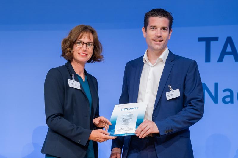Stellvertretend für das Projektkonsortium nimmt Florian Remark, Geschäftsführer der Strategion GmbH, die Auszeichnung für das Vorhaben SECAI von Dr. Daniela Brönstrup, Leiterin der Abteilung Digital- und Innovationspolitik im BMWK, entgegen. 