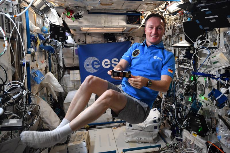 Matthias Maurer zeigt eine der Materialproben von Prof. Frank Mücklich auf der ISS. Rund sechs Monate verbrachte der deutsche ESA-Astronaut auf der Raumstation, wo er zahlreiche Experimente durchführte. Am 6. Mai 2022 war er wieder auf der Erde gelandet.