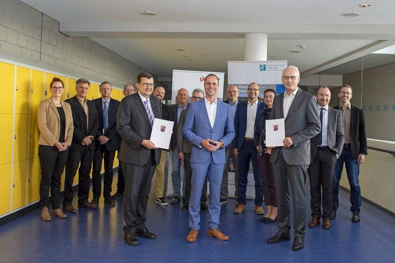 Wissenschaftsminister Clemens Hoch (Mitte) bei der Übergabe der Zuweisungsbescheide an Prof. Dr. Stefan Wehner (links vom Minister) und an Prof. Dr. Karl Stoffel (rechts vom Minister)