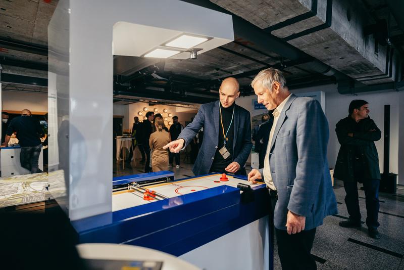 Ein Wissenschaftler erläutert einem Besucher das Roboter-Airhockey, bei dem verschiedene Reaktionszeiten des Roboters, von 3G bis 5G, im Spiel getestet werden können