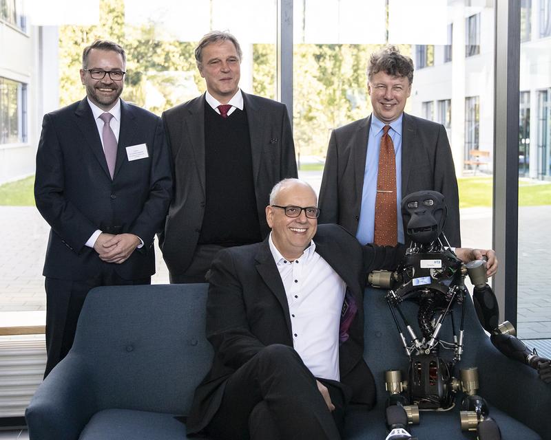 Gesellten sich zu Roboter Charlie (hinten von links): Tim Cordßen-Ryglewski, Prof. Dr. Frank Kirchner, Prof. Dr. Rolf Drechsler und Dr. Andreas Bovenschulte. Auf dem Bild fehlen Dr. Anna Christmann sowie Prof. Dr. Antonio Krüger, die live zugeschalte