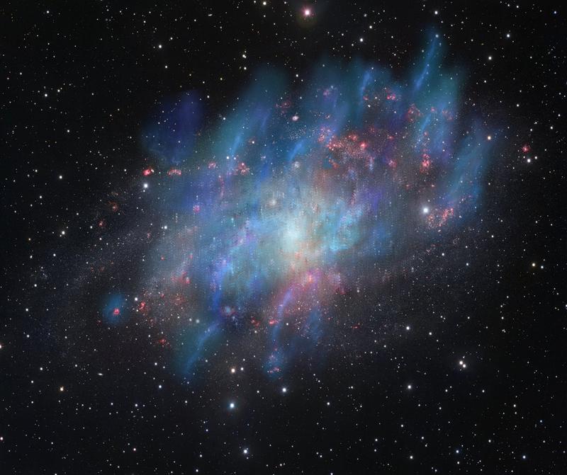 Künstlerische Illustration der von der kosmischen Strahlung angetriebenen Winde (blau und grün), überlagert von einem optischen Bild der Dreiecksgalaxie M33 (rot und weiß), das auf Beobachtungen mit dem VLT-Survey-Teleskop der ESO in Chile basiert.