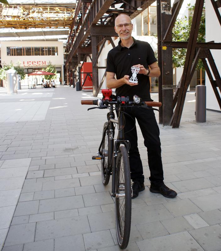 Als rote Version am Fahrradlenker, als hellgraue Version in den Händen: Prof. Dr.-Ing. Jürgen Adamek von der Hochschule Osnabrück hat eine neuartige Smartphone-Halterung erfunden und dafür nun ein Patent erhalten. 
