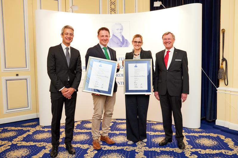 Timmy Klebb, Vorstandsvorsitzender der Deutschen Ärzteversicherung (l.) und Prof. Dr. Erland Erdmann, Vorsitzender des Kuratoriums Hufeland-Preis (r.), überreichten die Urkunden an die Preisträger Prof. Dr. Stefan Kölker und PD Dr. Ulrike Mütze.