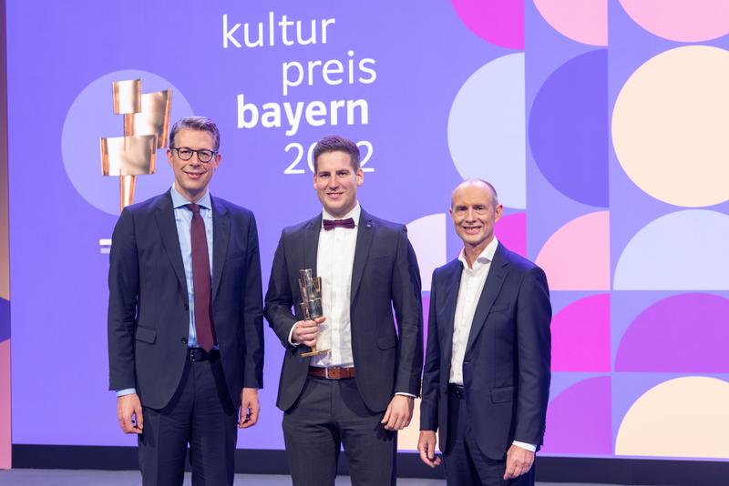 Der Bayerische Kunst- und Wissenschaftsminister Markus Blume (links) und Bayernwerk-Chef Dr. Egon Leo Westphal (rechts) freuen sich mit Preisträger Maximilian Fischer (Mitte). 