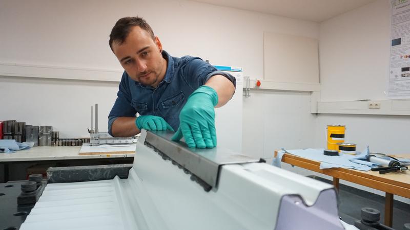 Florian Ilg, wissenschaftlicher Mitarbeiter im Institut für Material- und Bauforschung, bringt eine klebtechnische Verstärkung an auf einem Modell der Deckenunterseite eines Parkhauses