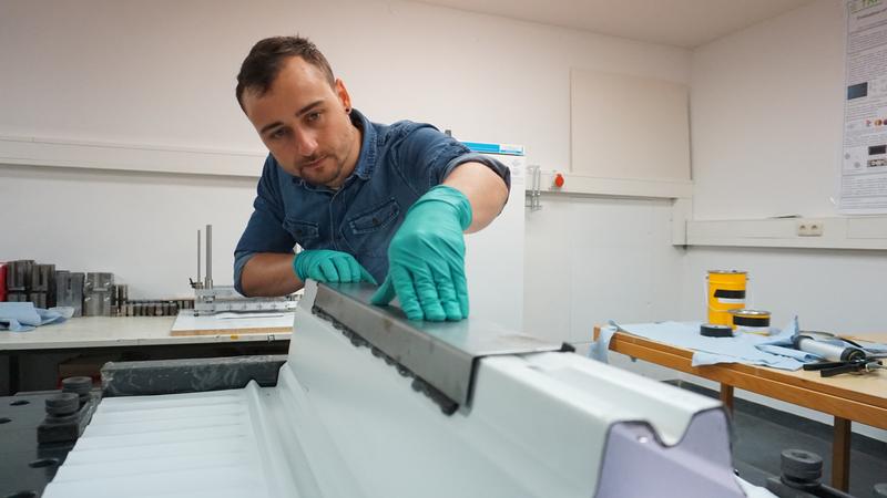 Florian Ilg, wissenschaftlicher Mitarbeiter im Institut für Material- und Bauforschung, bringt eine klebtechnische Verstärkung an auf einem Modell der Deckenunterseite eines Parkhauses