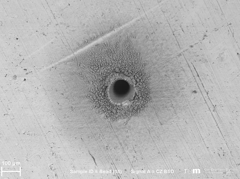 Das Loch, das der Strahl des tragbaren Lasergeräts pLA in die Oberfläche der Goldstücke schmilzt, misst lediglich 120 Mikrometer Durchmesser und ist konisch geformt. Nur durch ein Elektronenmikroskop lässt sich der Schaden am Goldobjekt erkennen.
