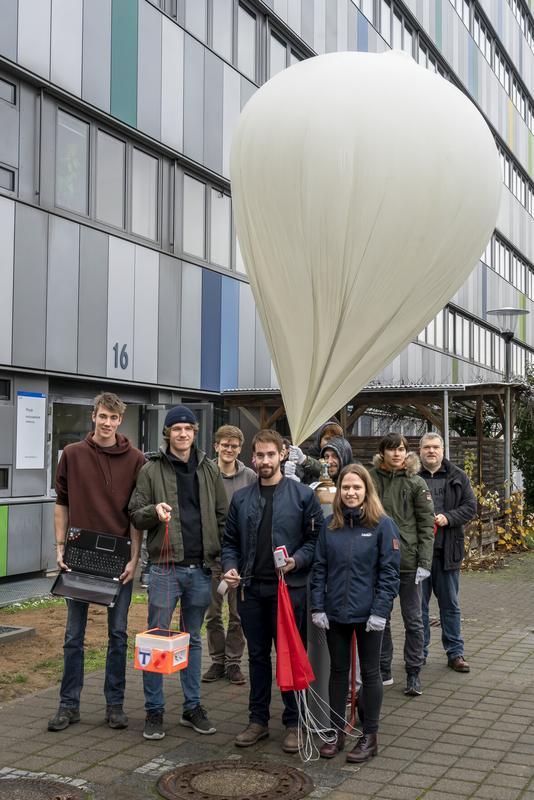 Das Projektteam aus Studierenden und Forschenden des II. Physikalischen Instituts mit dem Ballon und der orangefarbenen Sonde.