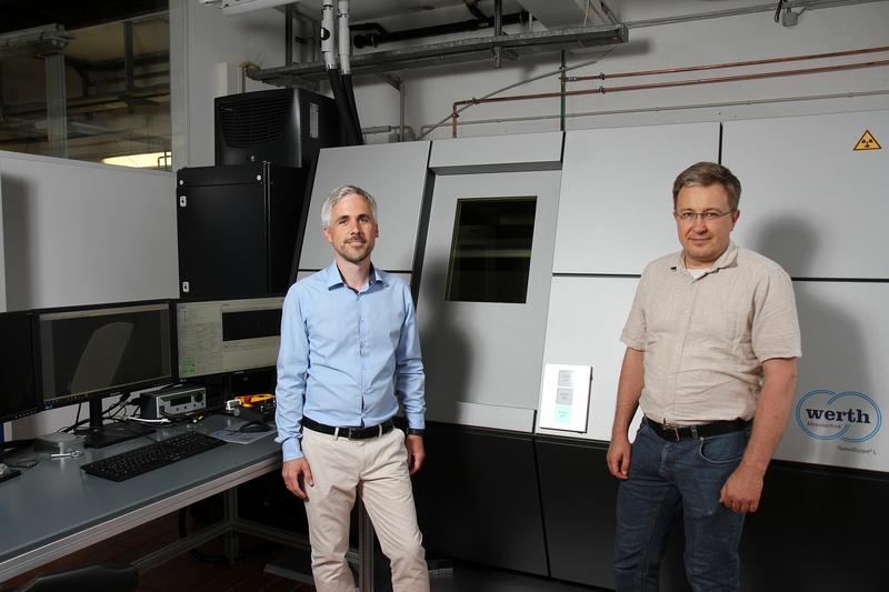 Dr.-Ing. Kai Nikolaus (links) und Prof. Sergiy Antonyuk vor dem CT-Gerät, das Strukturen ab 1 Mikrometer sichtbar machen kann. 
