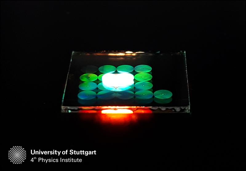 Photoaufnahme mehrerer Metalinsen auf einem Glassubstrat, die von oben mit weißem Licht beleuchtet werden. 