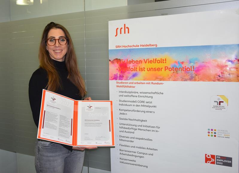 Anni Pröll, Diversity-Beauftragte der SRH Hochschule Heidelberg, hält das Zertifikat familiengerechte Hochschule in den Händen.