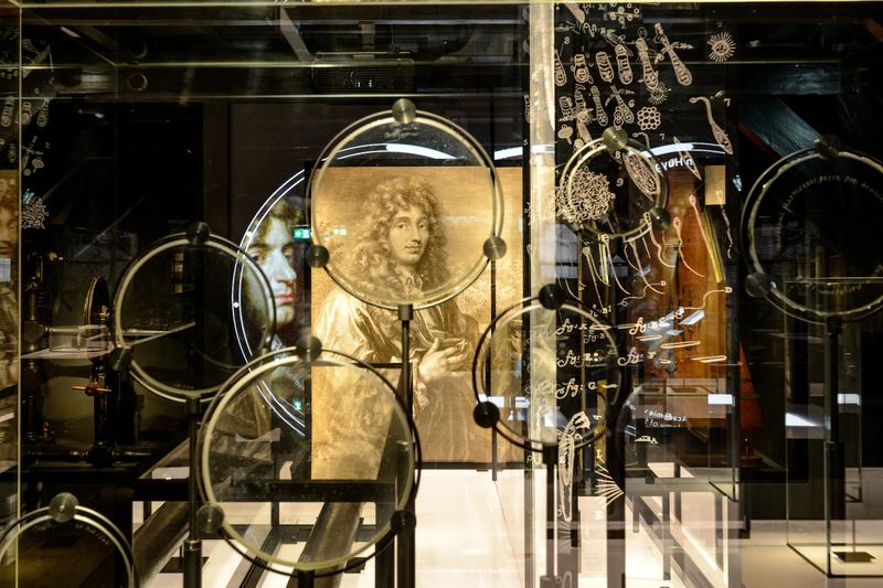 A collection of lenses by Christiaan Huygens with his portrait in the background.