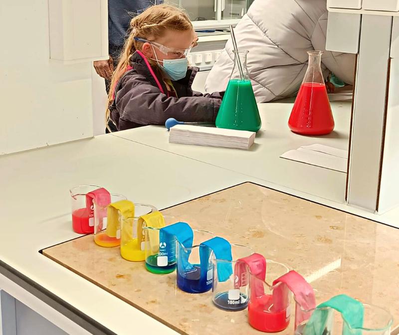 Ein Mädchen experimentiert beim Weltwassertag an der SRH Hochschule Heidelberg mit buntem Wasser.