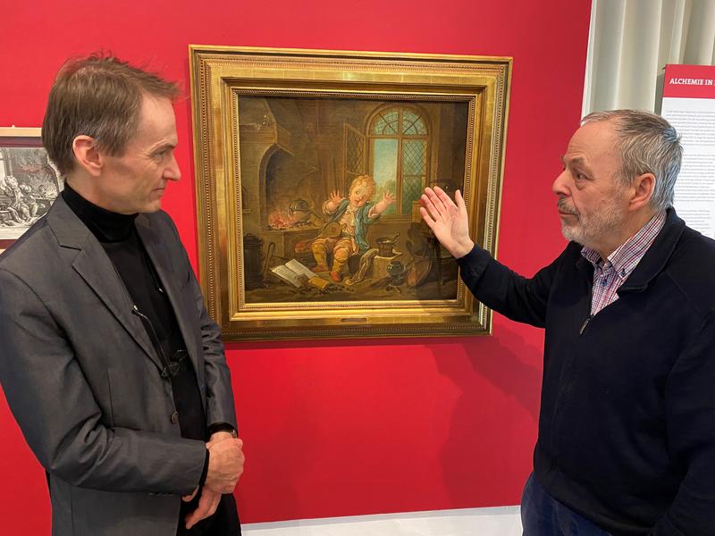 Der Sammler Dr. Wolfgang Hönle und der Kurator Dr. Michael Bischoff am Bild "Der kleine Alchimist", das in der aktuellen Sonderausstellung „Alchemie – Magie oder Naturwissenschaft?“ im Weserrenaissance-Museum Schloss Brake in Lemgo zu sehen ist.