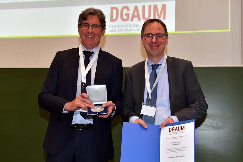Prof. Rolf Ellegast (re) erhält die Joseph-Rutenfranz-Medaille 2023 der Deutschen Gesellschaft für Arbeitsmedizin und Umweltmedizin (DGAUM) . Links Prof. Thomas Kraus, Präsident der DGAUM.