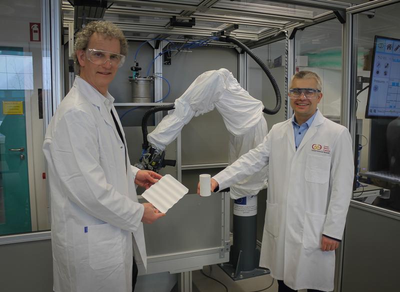 Prof. Dr. Dominik Henrich (li.) und Prof. Dr.-Ing. Stefan Schafföner (re.) vor einer Roboterzelle zur Herstellung von Bauteilen aus Faserverbundwerkstoffen.