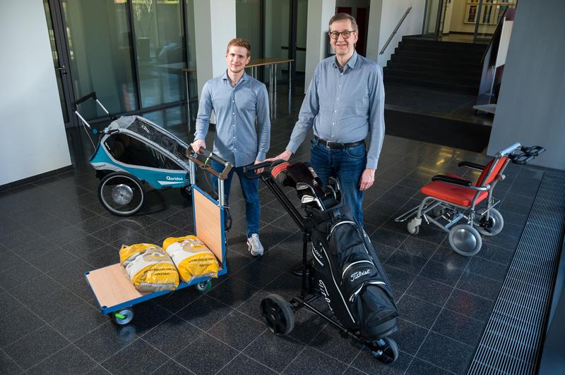 Professor Matthias Nienhaus (r.) und Ingenieur Eric Peleikis aus seinem Team inmitten von Forschungsobjekten: Überall, wo Menschen auf Räder angewiesen sind, kann die neue Technologie die Fahrt, das Lenken oder den Transport erheblich erleichtern.