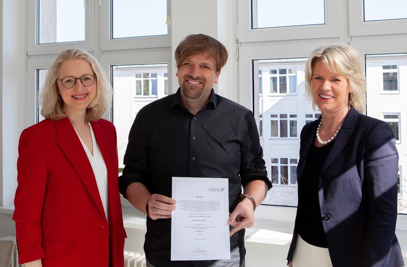 FHM-Rektorin Prof. Dr. Anne Dreier (rechts) und Medien-Dekanin Prof. Dr. Astrid Kruse (links) überreichten Stefan Finger die Urkunde zur Professur.