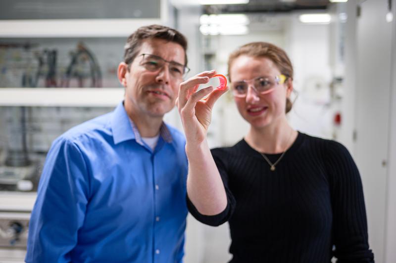 Professor Guido Kickelbick und Doktorandin Svenja Pohl mit einem farbigen Solarkonzentrator.