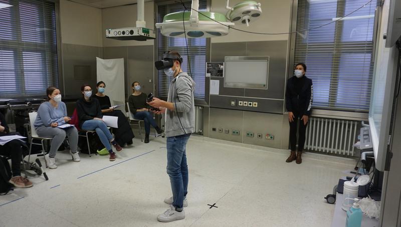 Virtual-Reality-Seminar an der Uni Würzburg. Die Studierenden verfolgen den Fall auf einer Leinwand rechts im Bild. 