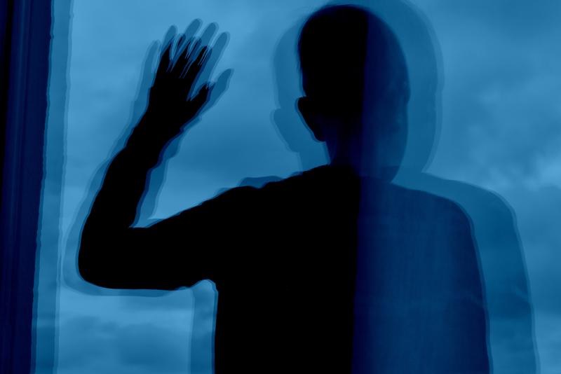 A person is reflected several times in a window pane. The bizarre superimposition of the reflections represents the altered sense of action of patients with schizophrenia.