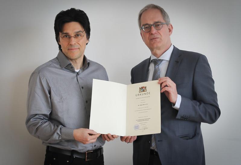 Prof. Dr. Claus Bässler erhält von Universitätspräsident Prof. Dr. Stefan Leible seine Ernennungsurkunde. 