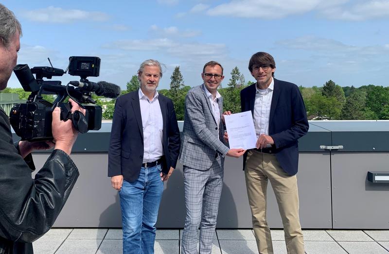 Digitalisierungsminister Dirk Schrödter (Mitte) übergibt an Prof. Jan Rupp (rechts) und Prof. Martin Leucker den Förderbescheid 