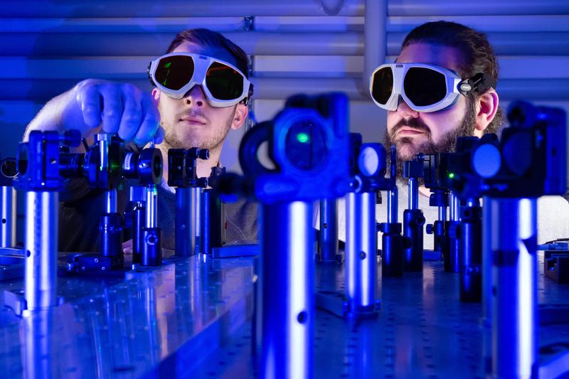 Die Doktoranden Paul Herrmann (l.) und Sebastian Klimmer experimentieren an einem Laser-Versuchsaufbau an der Universität Jena.