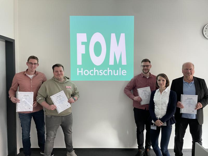 Mit der Urkunde vom Patentamt: (von links) Die FOM Studierenden Simon Börgel, Jan Limpak,  Marius Wachholz sowie Sabine Wengeler, stellevertretende Geschäftsleiterin der FOM in Dortmund,  und Prof. Dr. Jochen Remmel, Dozent für Konstruktionstechnik.