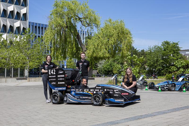 Das Formula Student Team der h_da am neuen Rennwagen "F 23": Studentischer Projektleiter Jonas Acker (Mitte stehend), Michelle Peters (links) und Vanessa Kreß (rechts) aus der Finanzleitung und sitzend Prof. Dr. Florian Van de Loo, Faculty Advisor.