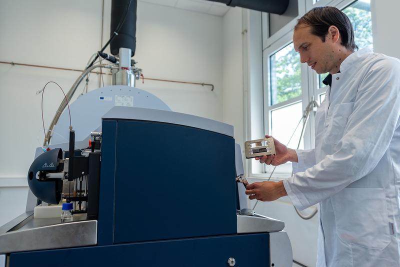 Dr. Nettersheim gibt einen Dünnschliff und eine Gesteins-Scheibe in ein 7T solariX XR FT-ICR-MS im Geobiomolecular Imaging Labor am MARUM. Das hochauflösende Massenspektrometer ist mit einer Laser-Desorptionsquelle ausgestattet ist. 