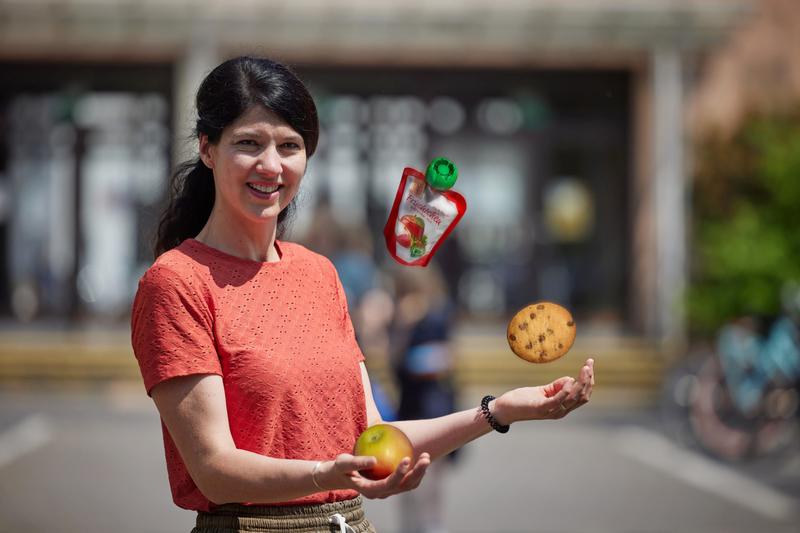 Stefanie Landwehr von der Marktforschung der Agrar- und Ernährungswirtschaft an der Universität Bonn „jongliert“ vor einer Schule mit Snacks. 