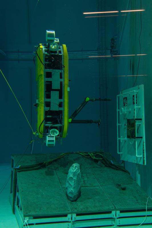 The AUV performs manipulation tasks on an underwater mockup in an upright position.